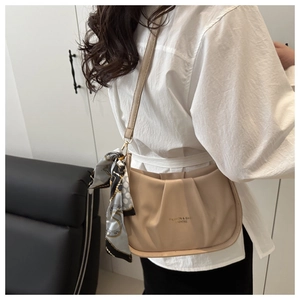 Détail du sac à bandoulière plissé beige avec foulard déco et logo élégant imprimé