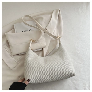 Detail of cream crescent bag featuring diagonal woven texture and adjustable strap