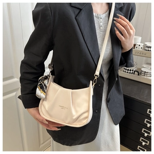 Détail du sac carré en cuir plissé beige avec un foulard en soie imprimé sur la bandoulière