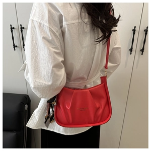 Détail du sac bandoulière rouge froncé avec lettrage doré et foulard en soie décoratif