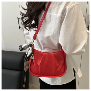 Dettaglio borsa rossa a pieghe con decorazione in foulard di seta e logo dorato