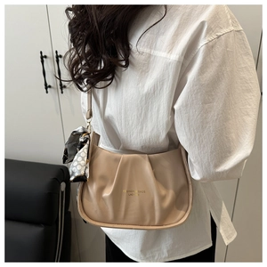 Dettaglio borsa a mezzaluna beige con pieghe logo moda e sciarpa di seta a pois