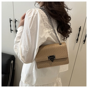 Detail of woven texture shoulder bag with metallic chain and square lock closure