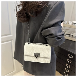 Detail of white woven leather texture flap bag with metal chain strap and lock clasp