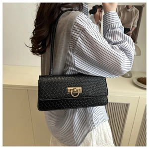 Detailed view of black woven baguette bag featuring a gold buckle and shoulder strap