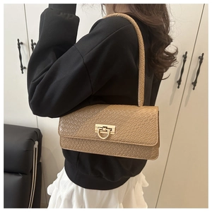 Détail du sac baguette marron à motif crocodile avec un fermoir doré en forme de D en métal