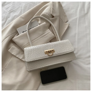 Detail of white croco-embossed baguette bag with a golden metal buckle and sleek handle