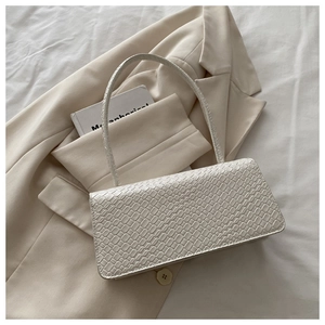 Close-up of white crocodile pattern embossed leather texture on a stylish baguette bag