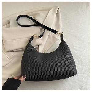 Detail of black hobo bag with twill texture, golden hardware and leather strap