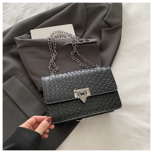 Detail of black woven texture square bag with silver metal twist lock and chain strap