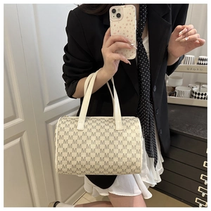 Detail view of cream Boston bag with dark brown M monogram pattern and sturdy top handles