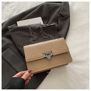 Close-up of woven texture embossed khaki leather bag with silver chain and metal buckle
