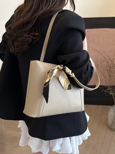Borsa a tracolla vintage beige con foulard decorativo indossata da modella per primavera