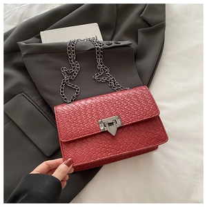 Detail of red woven texture handbag featuring a silver lock and metal chain strap