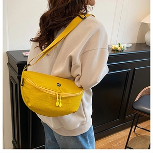 Close-up of bright yellow nylon crescent crossbody bag with OK patch and double zippers