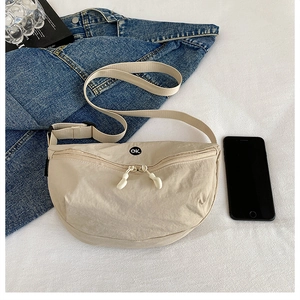 Close-up of off-white crescent crossbody bag with round OK embroidery and wide strap