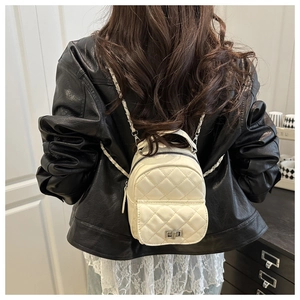 Detail of white quilted mini backpack with diamond pattern and metal chain strap
