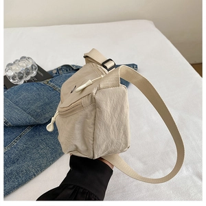 Detail of beige nylon crossbody bag showing the front pocket with white drawstring cord