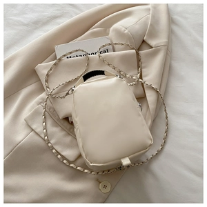 Detail of a beige mini handbag with chain strap on a blazer for a stylish look