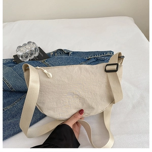 Detail of beige crescent nylon tote bag with wide strap and minimalist hardware