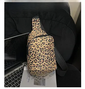 Close-up of leopard print crossbody bag on sofa with books and laptop