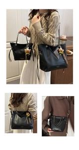 Detail of black leather tote bag with metal chain strap and cute bear charm pendant