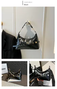 Detail of black patent leather shoulder bag with gold metal buckles and rivet accents