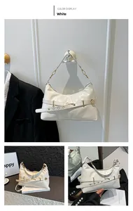 Detailed view of white glossy leather shoulder bag with light gold adjustable buckle strap