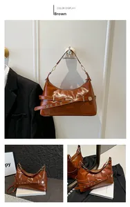 Detail view of brown vintage leather crossbody bag with decorative belts and gold hardware