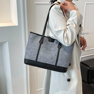Minimalist grey felt tote bag with black leather straps shown on a model shoulder