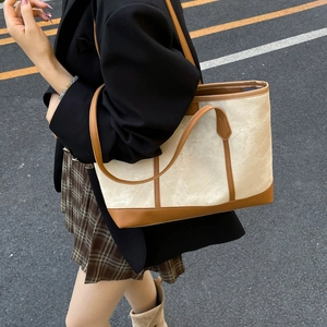 Grand sac fourre-tout en toile minimaliste avec garniture en cuir marron porté par un mannequin