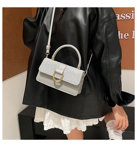 Close-up of minimalist square crossbody bag with glitter flap and golden U-shaped buckle