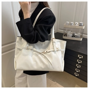 Detail of white glossy leather tote bag with decorative buckle strap and slim shoulder strap
