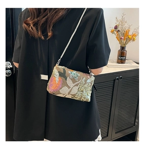 Detail of embroidered sequin crossbody bag with floral patterns and silver chain strap