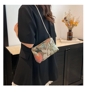 Detailed embroidery and sequins on a floral crossbody bag with metallic chain