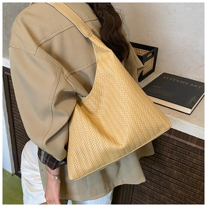 Detail of cream woven shoulder tote bag featuring intricate herringbone pattern texture