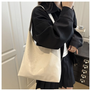Detail of off-white minimalist tote bag showing wide shoulder strap and soft leather texture