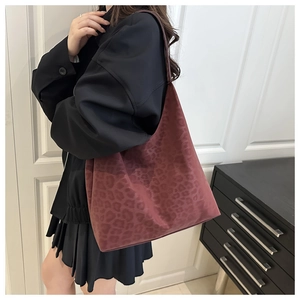 Detail view of large leopard print tote bag in dark burgundy red worn by model