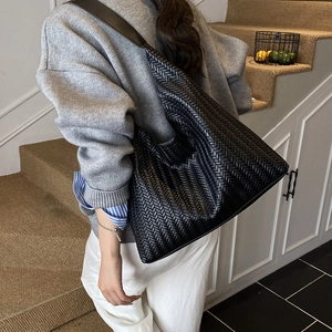 Grand sac cabas tressé noir avec bandoulière large porté pour un look chic et décontracté