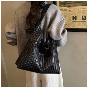 Detail view of black woven faux leather tote bag showing intricate V-shape texture