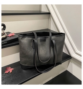 Detail of dark grey canvas tote bag with black leather trim on minimalist stairs