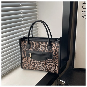 Détail du sac léopard avec garniture en cuir noir et fermeture éclair dorée élégante
