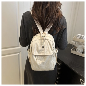 Dettaglio dello zaino in nylon beige con tasche a zip e trama del tessuto testurizzato