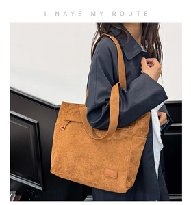 Brown corduroy tote bag with front zipper pocket shown on a shoulder for daily commute