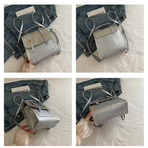 Detail view of the silver woven texture and gold metal buckle on a faux leather backpack