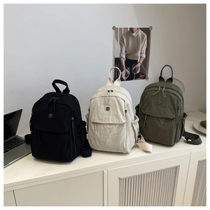Three colors of lightweight nylon backpacks in black, off-white, and dark green displayed