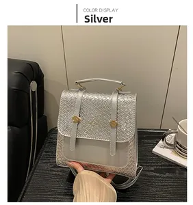 Detail of silver quilted backpack featuring golden circular metal hardware and hand strap