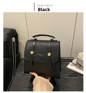 Detail of a black woven leather handbag featuring a gold metal ring and top handle