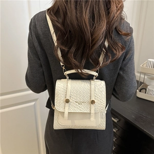 White textured leather convertible handbag with gold buckle shown on female model