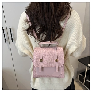 Detail of pink faux crocodile skin texture and gold buckle straps on dual-use backpack